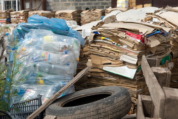 Separate collection of garbage in the form of a bag with plastic bottles and briquettes with cardboard lies in an open warehouse, prepared for recycling.