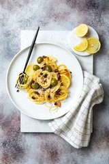 Italian pasta cacio e pepe, spaghetti mixed with grated cheese, green olives, lemon and raisins