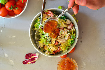 Vegan Bowl. Vegetable salad with avocado, tomatoes, herbs, iceberg lettuce, lettuce, sweet and sour sauce and yogurt. Healthy vegetarian lunch. Salad in a gray clay bowl on a gray concrete background.