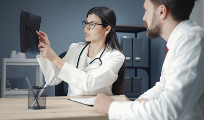Two doctors male female watch patient's x-ray results, mentor intern discuss roentgenogram