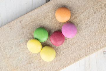 Group of six whole sweet colourful candy on wooden cutting board flatlay on white wood