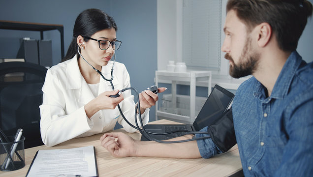 Female practitioner check patient' pressure using stethoscope manual sphygmomanometer at workplace