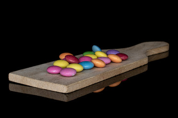 Obraz na płótnie Canvas Lot of whole sweet colourful candy on wooden cutting board isolated on black glass