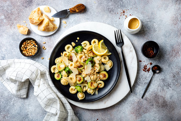 Fresh homemade italian pasta cappelletti with roasted brussels sprouts, pine nuts, parmesan cheese, lemon sauce and red chili flakes