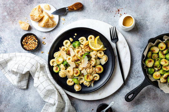 Fresh Homemade Italian Pasta Cappelletti With Roasted Brussels Sprouts, Pine Nuts, Parmesan Cheese, Lemon Sauce And Red Chili Flakes