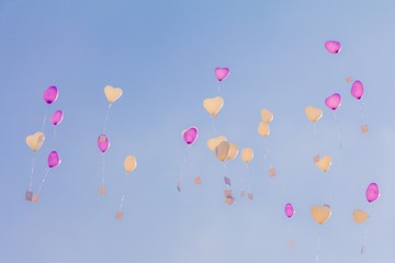 Heart love balloons fly into blue sky with ceremony wishes. Romantic symbol of future partnership. Group of beautiful heart ballons with congratulations cards at wedding party or valentines day