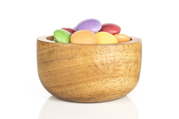 Lot of whole sweet colourful candy in bamboo bowl isolated on white background
