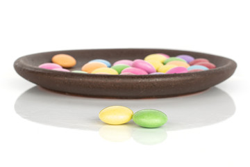 Obraz na płótnie Canvas Lot of whole sweet colourful candy front focus with brown ceramic coaster isolated on white background