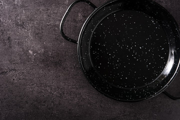 Paella pan kitchenware in black background top view. Copy space
