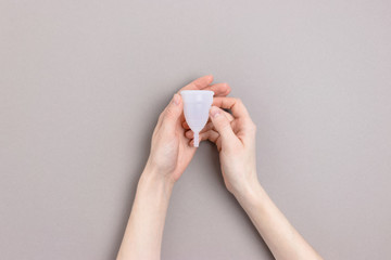 Hands hold menstrual cup. Minimalicstic zero waste concept on gray background.