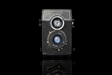 One whole vintage camera isolated on black glass