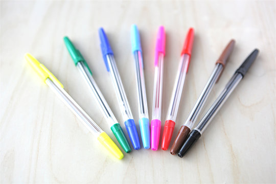 Rainbow ball point pens on wooden table