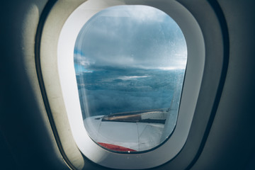 View from an airplane window, we fly above the clouds with a clear blue sky, we also see a piece of...