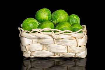Lot of whole fresh green brussels sprout in bast basket isolated on black glass