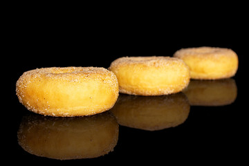 Group of three whole sweet golden mini cinnamon donut isolated on black glass