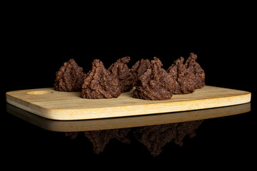 Group of seven whole homemade brown coconut cocoa biscuit on bamboo cutting board isolated on black glass