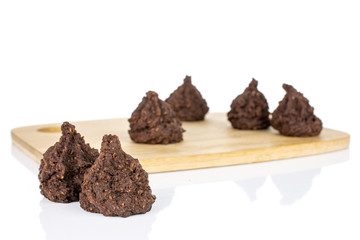 Group of six whole homemade brown coconut cocoa biscuit on bamboo cutting board isolated on white background