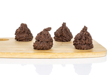 Group of four whole homemade brown coconut cocoa biscuit on bamboo cutting board isolated on white background