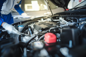 The auto mechanic in the auto repair shop is checking the engine. For customers who come to use the service for checking The technician will work in the service center.