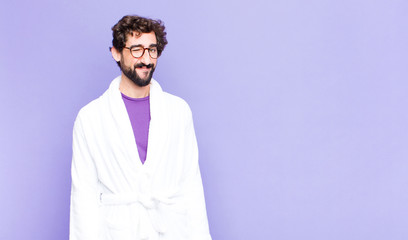 young bearded man wearing bathrobe looking happy and friendly, smiling and winking an eye at you...