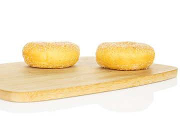 Group of two whole sweet golden mini cinnamon donut on bamboo cutting board isolated on white background