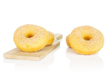 Group of four whole sweet golden mini cinnamon donut on small wooden cutting board isolated on white background