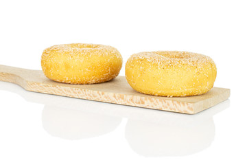 Group of two whole sweet golden mini cinnamon donut on small wooden cutting board isolated on white background