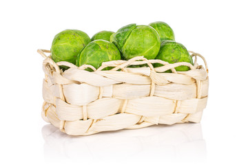 Lot of whole fresh green brussels sprout in bast basket isolated on white background