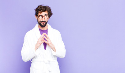 young bearded man wearing bathrobe scheming and conspiring, thinking devious tricks and cheats,...