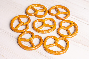 Group of seven whole salty brown pretzel on white wood