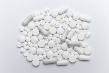 Prescription drugs, pills and capsules of white colors. On white background.