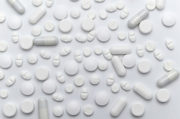 Prescription drugs, pills and capsules of white colors. On white background.