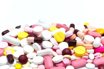 Prescription drugs, pills, capsules and tablets of different colors all mixed in. On white background. Selective focus and Copy space.