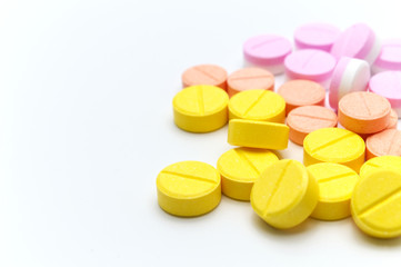 Pile of prescription drugs, pills and tablets of different colors, Orange Yellow and pink on a white background.  Selective focus and Copy space.