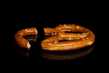 One whole salty brown pretzel isolated on black glass