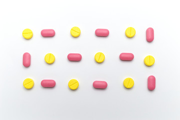 Prescription drugs, pills and tablets of different colors between yellow and pink colors supplements for the treatment and health care on a white background.
