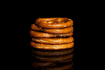 Group of five whole salty brown pretzel isolated on black glass