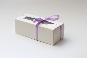 White cardboard box with a transparent top tied with a lilac ribbon isolated on a white background. A wonderful gift for Valentine's Day, birthday.
