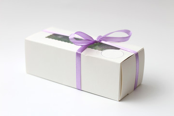White cardboard box with a transparent top tied with a lilac ribbon isolated on a white background. A wonderful gift for Valentine's Day, birthday.