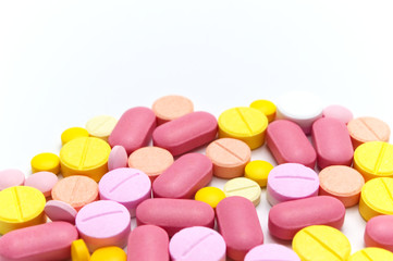 Prescription drugs, pills, capsules and tablets of different colors all mixed in. On white background. Selective focus and Copy space.