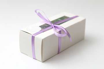 Obraz premium White cardboard box with a transparent top tied with a lilac ribbon isolated on a white background. A wonderful gift for Valentine's Day, birthday.