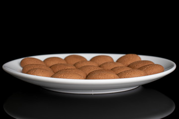 Lot of whole sweet brown chocolate sponge biscuit on white ceramic plate isolated on black glass