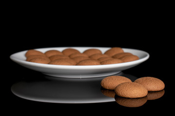 Lot of whole sweet brown chocolate sponge biscuit on white ceramic plate isolated on black glass