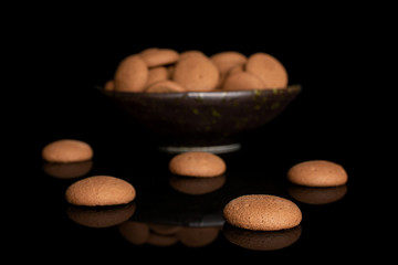 Lot of whole sweet brown chocolate sponge biscuit in dark ceramic bowl isolated on black glass