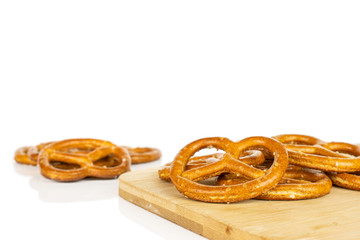 Lot of whole salty brown pretzel on bamboo cutting board isolated on white background