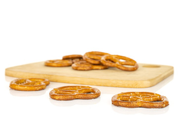 Lot of whole salty brown pretzel on bamboo cutting board isolated on white background