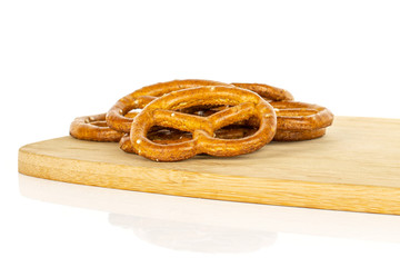 Lot of whole salty brown pretzel on bamboo cutting board isolated on white background