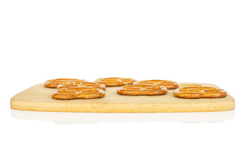 Group of seven whole salty brown pretzel on bamboo cutting board isolated on white background