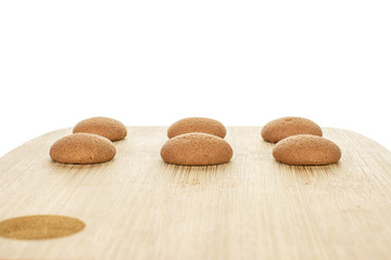 Group of six whole sweet brown chocolate sponge biscuit on bamboo cutting board isolated on white background