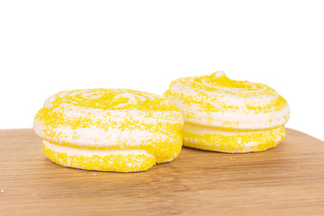 Group of two whole yellow sweet meringue on bamboo cutting board isolated on white background